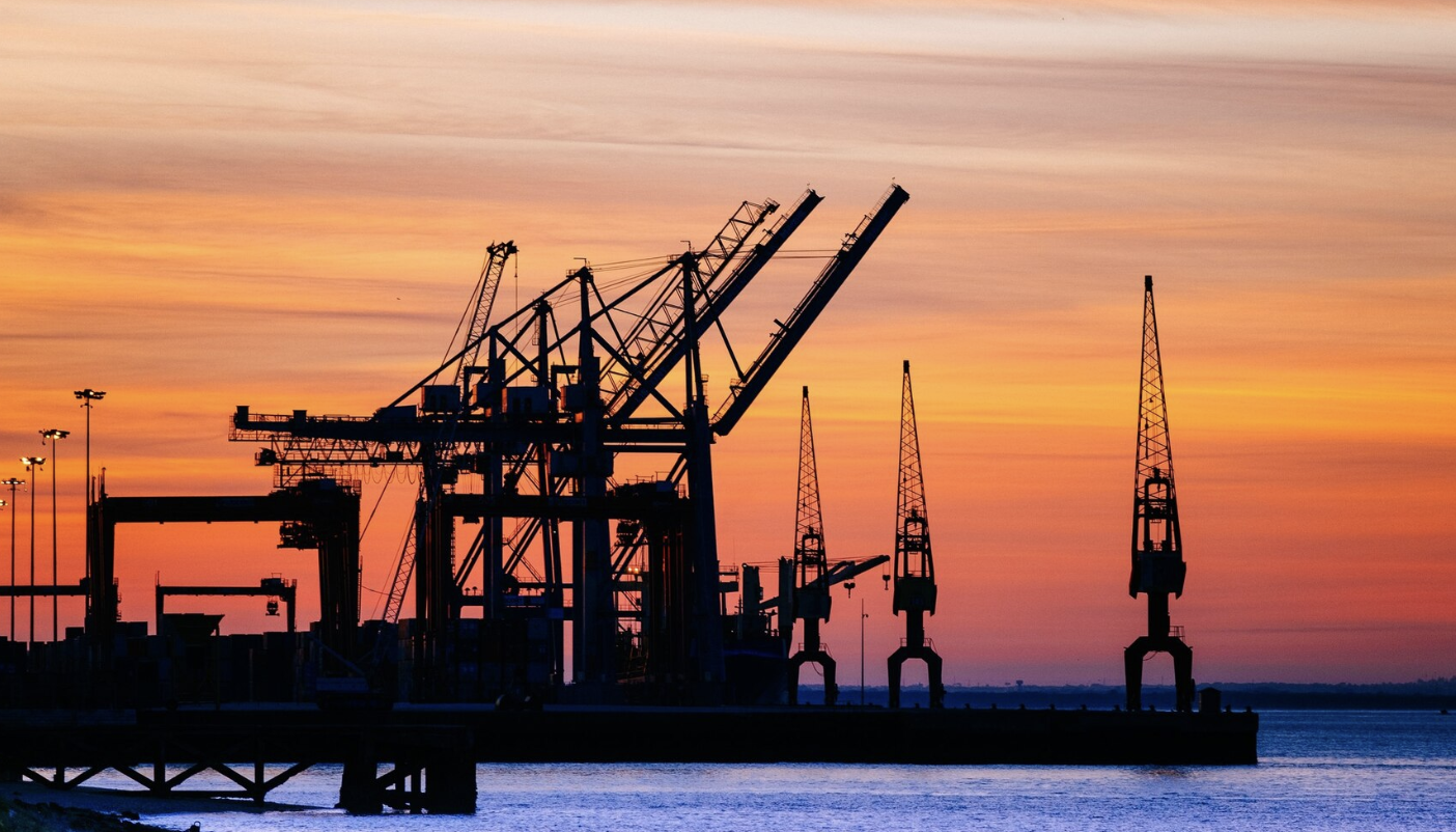 Industrial port with shipping cranes at sunset - representing OGCTA's expertise in maritime and oil & gas industry training
